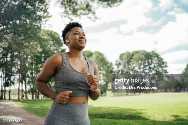 mujer corriendo en el parque con auriculares - entrenamiento deportivo fotografías e imágenes de stock