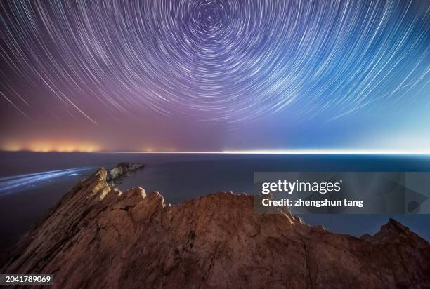star trails with the foreground of high cliff - north star stock pictures, royalty-free photos & images