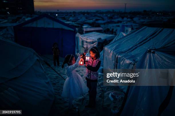 Palestinian children taking refuge in Tel al-Sultan region due to Israeli attacks decorate their tents with Ramadan lanterns and illuminate lights...