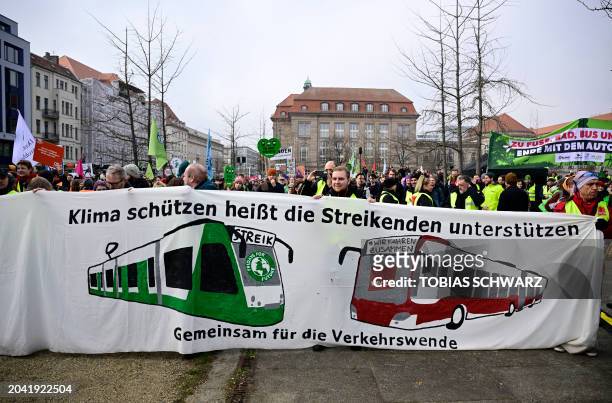 Demonstrators hold up a banner depicting a bus and a tramway and reading "Protecting the climate means supporting the striking people - together for...