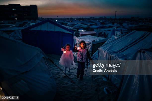 Palestinian children taking refuge in Tel al-Sultan region due to Israeli attacks decorate their tents with Ramadan lanterns and illuminate lights...