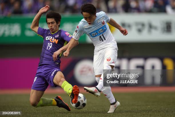 Koji Miyoshi of Consadole Sapporo is tackled by Sho Sasaki of Sanfrecce Hiroshima during the J.League J1 match between Sanfrecce Hiroshima and...