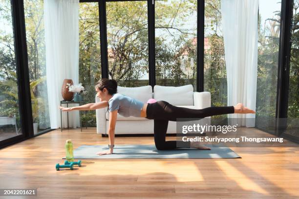 beautiful young woman doing yoga or exercise in living room at home, healthy lifestyle or sports training concept. - fitness or vitality or sport and women photos et images de collection