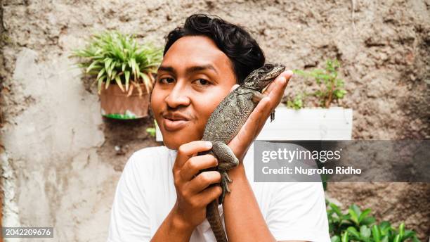 man put lizard pet beside his face - green iguana stock pictures, royalty-free photos & images