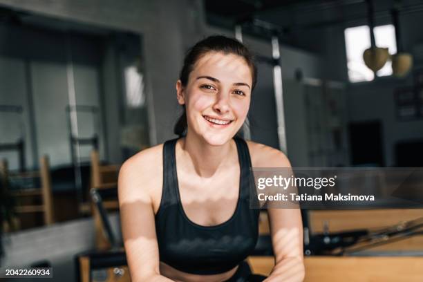 a fitness trainer in the gym on a sunny day, a smiling middle-aged woman in a black tracksuit. - topics stock pictures, royalty-free photos & images