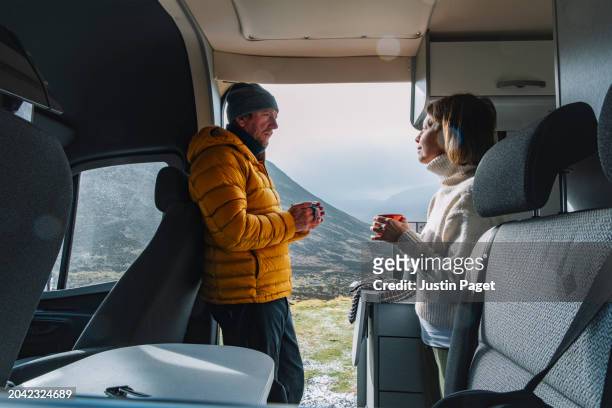a mature couple have a cup of tea in their campervan in the cairngorms, scotland - thier stock pictures, royalty-free photos & images