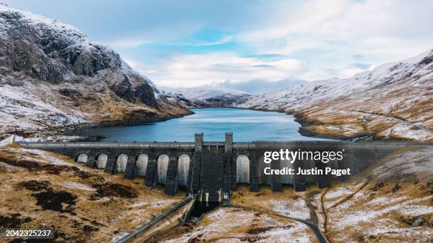 a majestic drone/aerial view over a hydroelectric dam in scotland on a winter's day - natural phenomena stock pictures, royalty-free photos & images