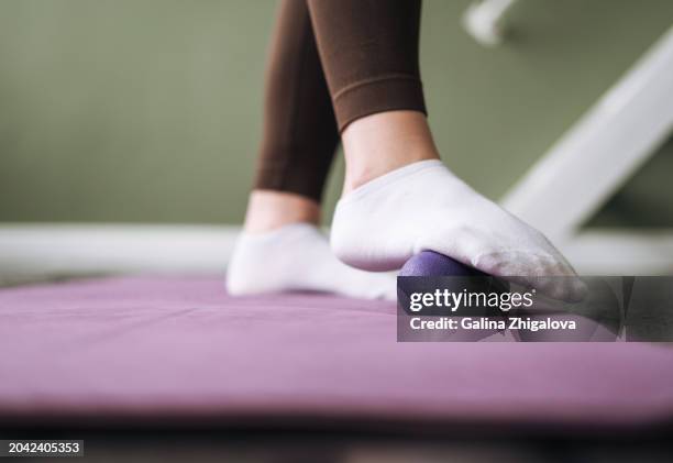 young woman in sports uniform doing self-massage with massage ball after fitness exercises at home - massage ball stock pictures, royalty-free photos & images