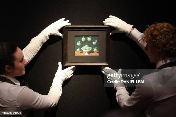 Gallery staff pose with an artwork entitled an artwork "Le principe d'Archimede" by Belgian artist Rene Magritte, during a press preview at...