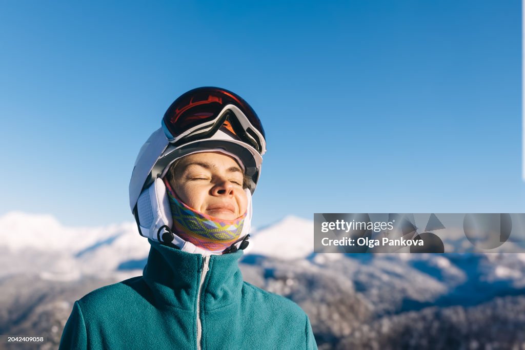 Portrait of a middle-aged woman enjoying the sun while skiing snowboarding in the mountains