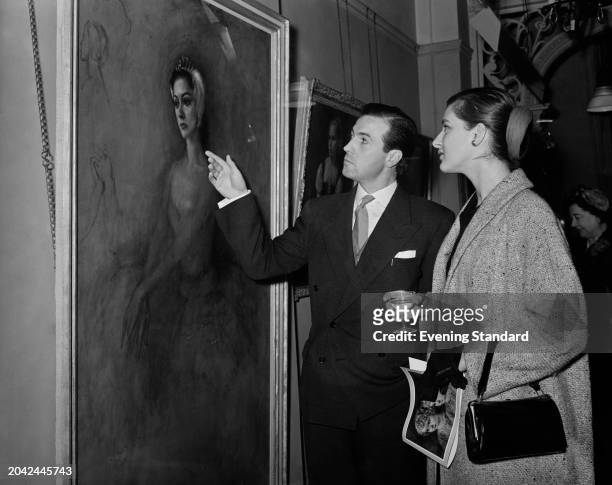 Artist Bernard Powell shows actress Caroline Blakiston an artwork at an exhibition of his paintings, November 14th 1955.