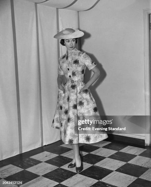 Evening Standard fashion model Gillian Tate wearing a sunhat and floral patterned day dress with pockets, London, February 17th 1956.