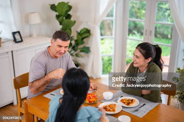a young family having fun while having supper together and eating pizza - italian mother kitchen stock pictures, royalty-free photos & images