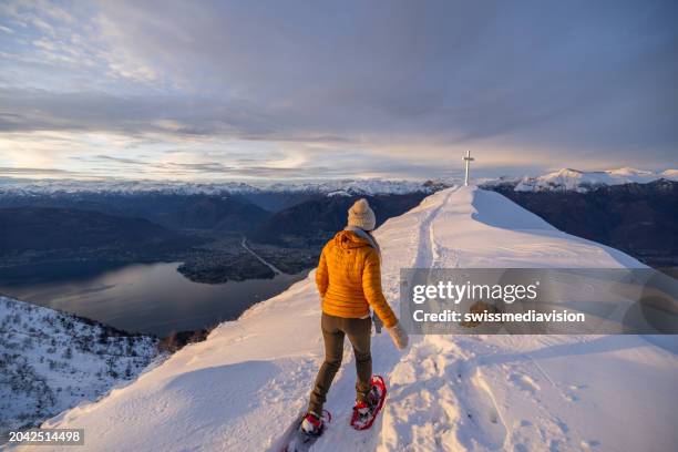 female hiker snowshoeing on mountain top at sunrise - locarno stock pictures, royalty-free photos & images