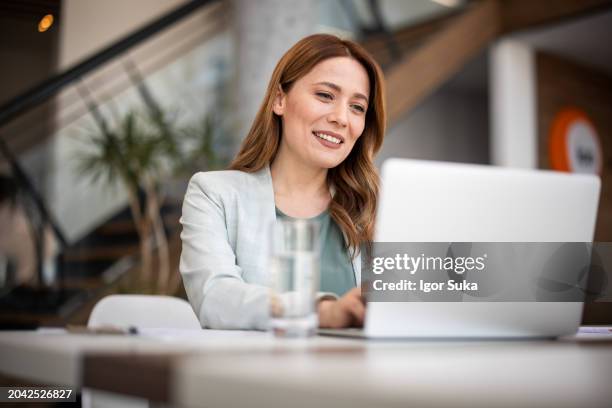 successful businesswoman using laptop, working in office. business technology corporate concept - woman smiling at computer stock pictures, royalty-free photos & images