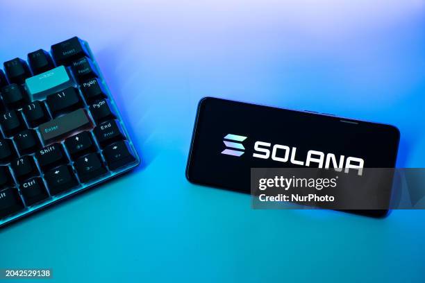 Mobile phone is displaying the logo of Solana cryptocurrency next to a keyboard.