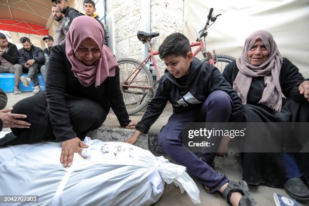 Palestinian women and a child mourn over the body of a relative killed during overnight Israeli bombardment on Deir al-Balah in the central Gaza...