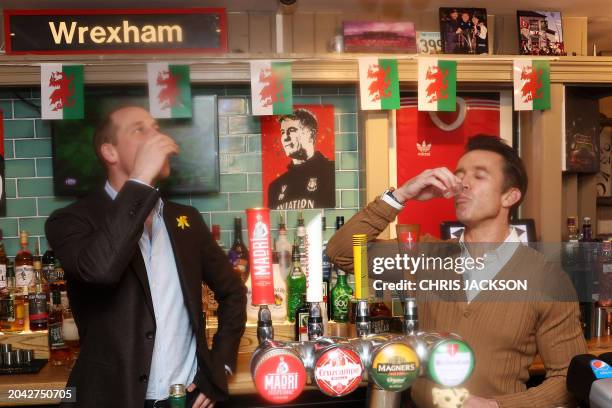 Britain's Prince William, Prince of Wales and co-chairman of Wrexham AFC Rob McElhenney take a drink behind the bar during a visit to the The Turf...