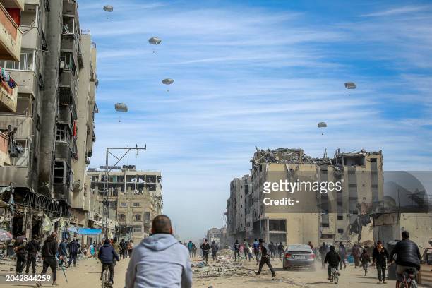 Palestinians run along a street as humanitarian aid is airdropped in Gaza City on March 1 amid the ongoing conflict between Israel and the Hamas...