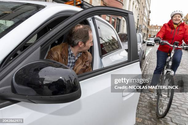 Car driver opens the door of his car with the 'Dutch reach' method, making the driver turn and look into the rear view mirror and over the shoulder...