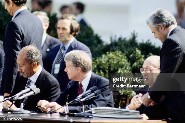 President Jimmy Carter looks on as Egyptian President Anwar Sadat and Israeli Prime Minister Menachem Begin sign the Camp David Accords Peace Treaty...