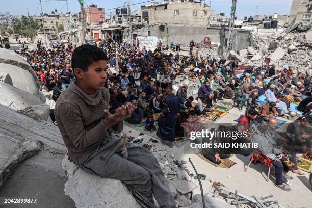 Young Palestinian boy sits on rubble as he attends the Friday noon prayers near the ruins of the al-Faruq mosque, destroyed in Israeli strikes in...