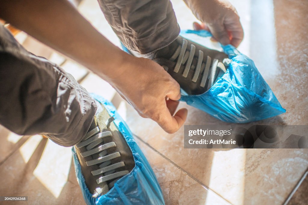 Close up of a man's hands putting on blue shoe covers