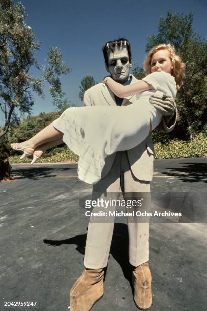 Austrian actress Barbara May, wearing a white dress, held in the arms of Frankenstein's Monster during a visit to Universal Studios in Universal...