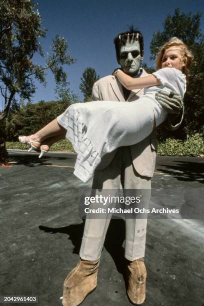 Austrian actress Barbara May, wearing a white dress, held in the arms of Frankenstein's Monster during a visit to Universal Studios in Universal...