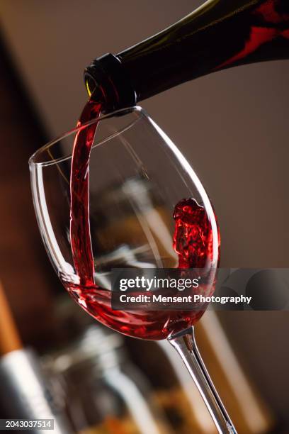 freeze motion in pouring red wine into the glass in bubbles - wine bottle stock pictures, royalty-free photos & images