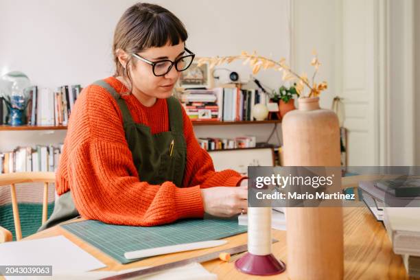 young woman working at home binding craft books - cutting mat stock pictures, royalty-free photos & images