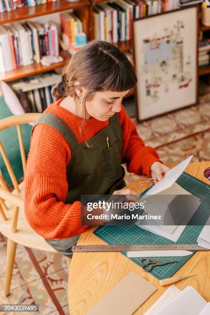 young woman working at home binding craft books - cutting mat stock pictures, royalty-free photos & images