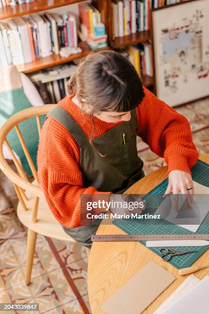 young woman working at home binding craft books - cutting mat stock pictures, royalty-free photos & images