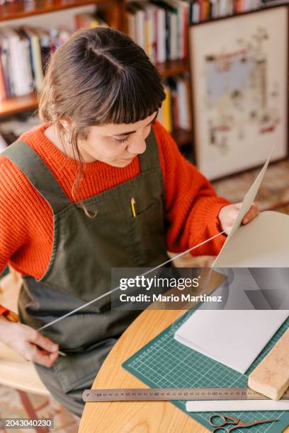 young woman working at home binding craft books - cutting mat stock pictures, royalty-free photos & images