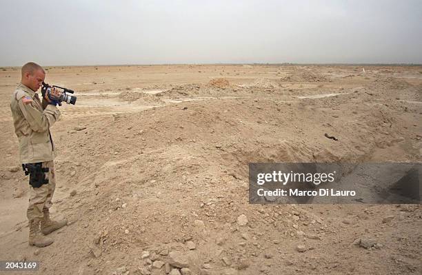 Officer from the 3rd 52nd Civil Affairs Commander, a member of a forensic team, uses a video camera to record the site of a mass grave May 30, 2003...