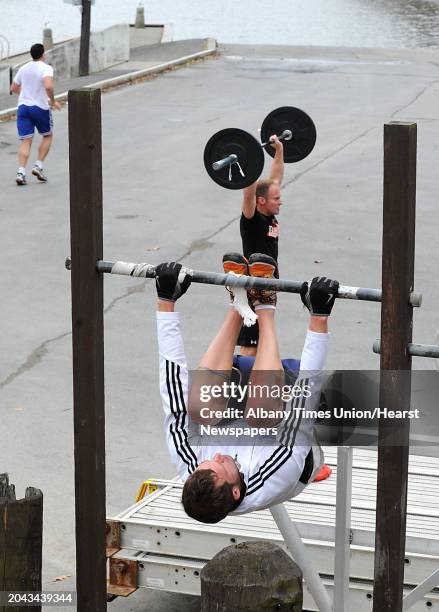 Scott Hayes of Broadalbin does some toes to bar reps and Jon Marshall of Schenectady does some thrusters with a bar bell at the Corning Preserve on...