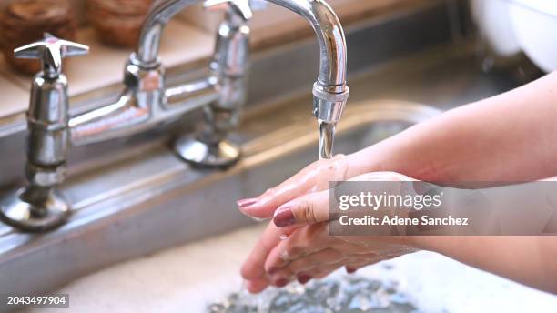 tap in kitchen, woman washing hands and water with bubbles for health, wellness and hand care in apartment. housework, cleaning and hygiene, soap detergent for kitchenware and skin on morning routine - kitchen utensil stock pictures, royalty-free photos & images