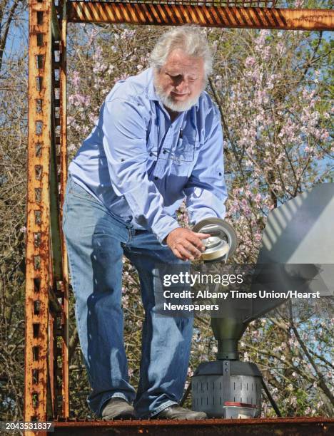 Larry Syzdek, an aerobiologist who counts pollen for a national database, uses a scientific vacuum called a Burkard at his pollen station at his farm...