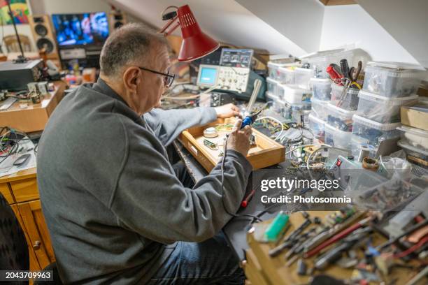 senior man repairing electrical equipment at home - barney stock pictures, royalty-free photos & images