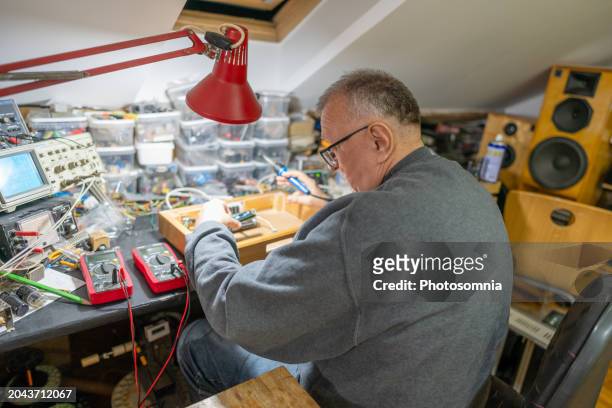 senior man repairing electrical equipment at home - barney stock pictures, royalty-free photos & images