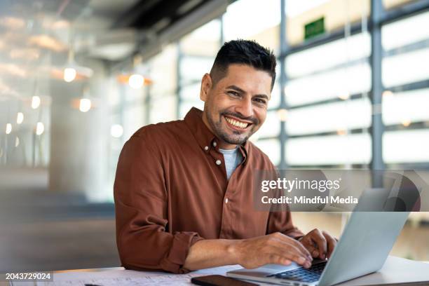 front view of latin american business manager working at desk with laptop computer - entrepreneur stockfoto's en -beelden