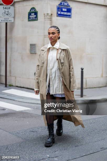 Guest wears beige trench coat, tights, beige bag, button shirt, blue skirt outside Victoria/Tomas during the Womenswear Fall/Winter 2024/2025 as part...