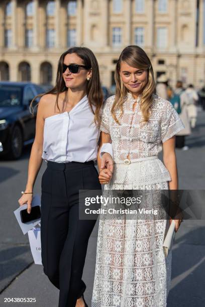 Anne-Laure Mais wears white asymmetric button shirt, black high waisted pants, white bag, sunglasses & Claire Rose Cliteur wears white laced skirt,...