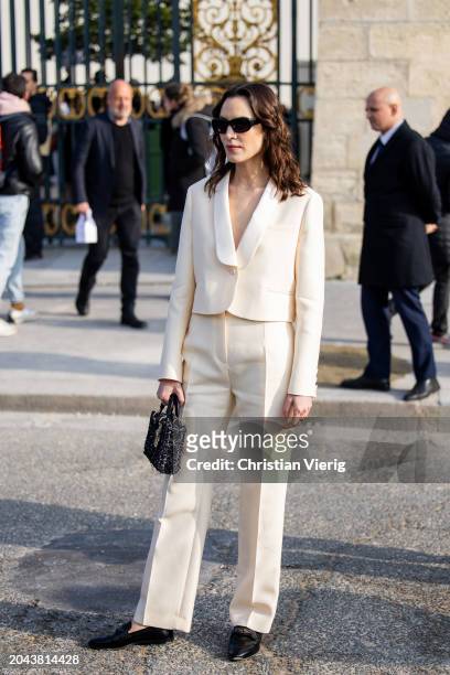 Alexa Chung wears beige suit, black bag, sunglasses outside Dior during the Womenswear Fall/Winter 2024/2025 as part of Paris Fashion Week on...