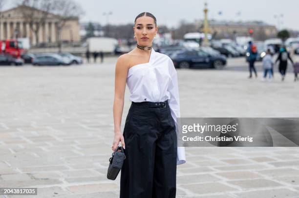 Ginevra Mavilla wears asymmetric white shirt, black high waisted pants, bag outside Dior during the Womenswear Fall/Winter 2024/2025 as part of Paris...