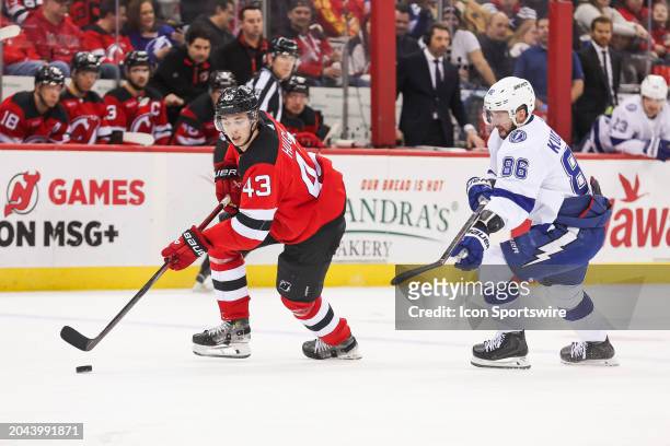 New Jersey Devils defenseman Luke Hughes skates with the puck while being chased by Tampa Bay Lightning right wing Nikita Kucherov during a game...