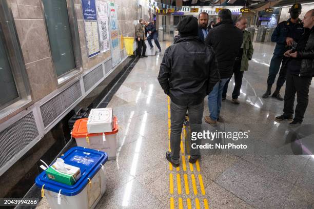 Unidentified officials are standing next to two mobile ballot boxes at an underground station in southern Tehran during the Parliamentary and...