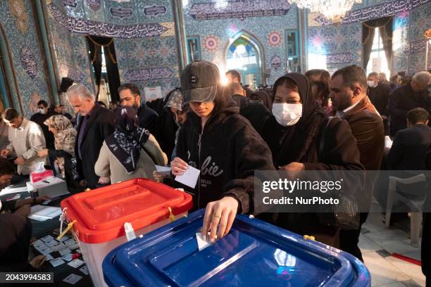 Young Iranian woman is wearing a hat and casting her first-ever ballot at a polling station in downtown Tehran, Iran, on March 1 during the...