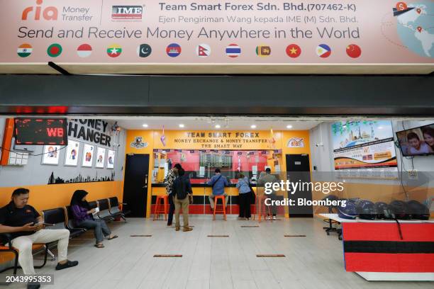 Customers at a currency exchange store in Kuala Lumpur, Malaysia, on Friday, March. 1, 2024. Policymakers have stepped up their rhetoric to rein in...