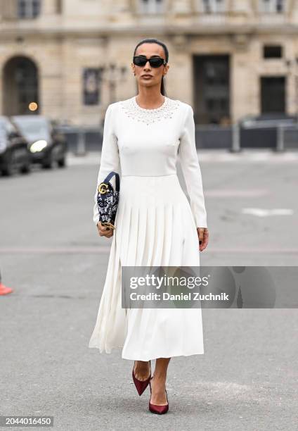 Guest is seen wearing a white red beaded Dior top, white panel Dior skirt, red heels, black and white with gold Dior bag and black sunglasses outside...